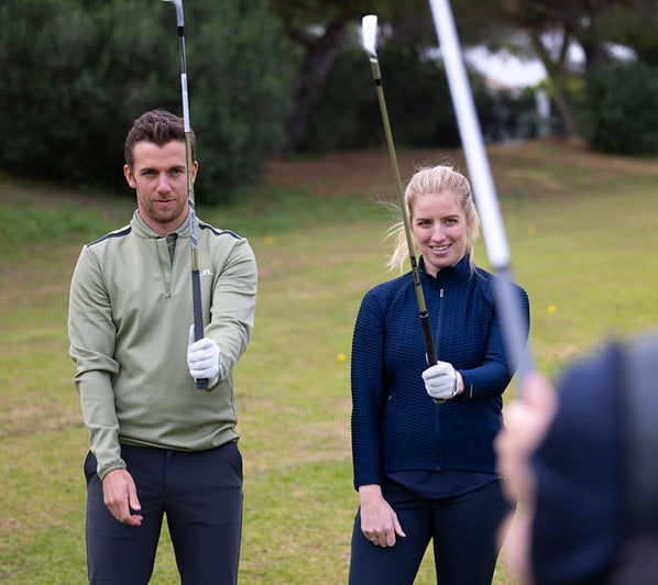 Twee mensen die uitleg krijgen over het vasthouden van de golfclub.